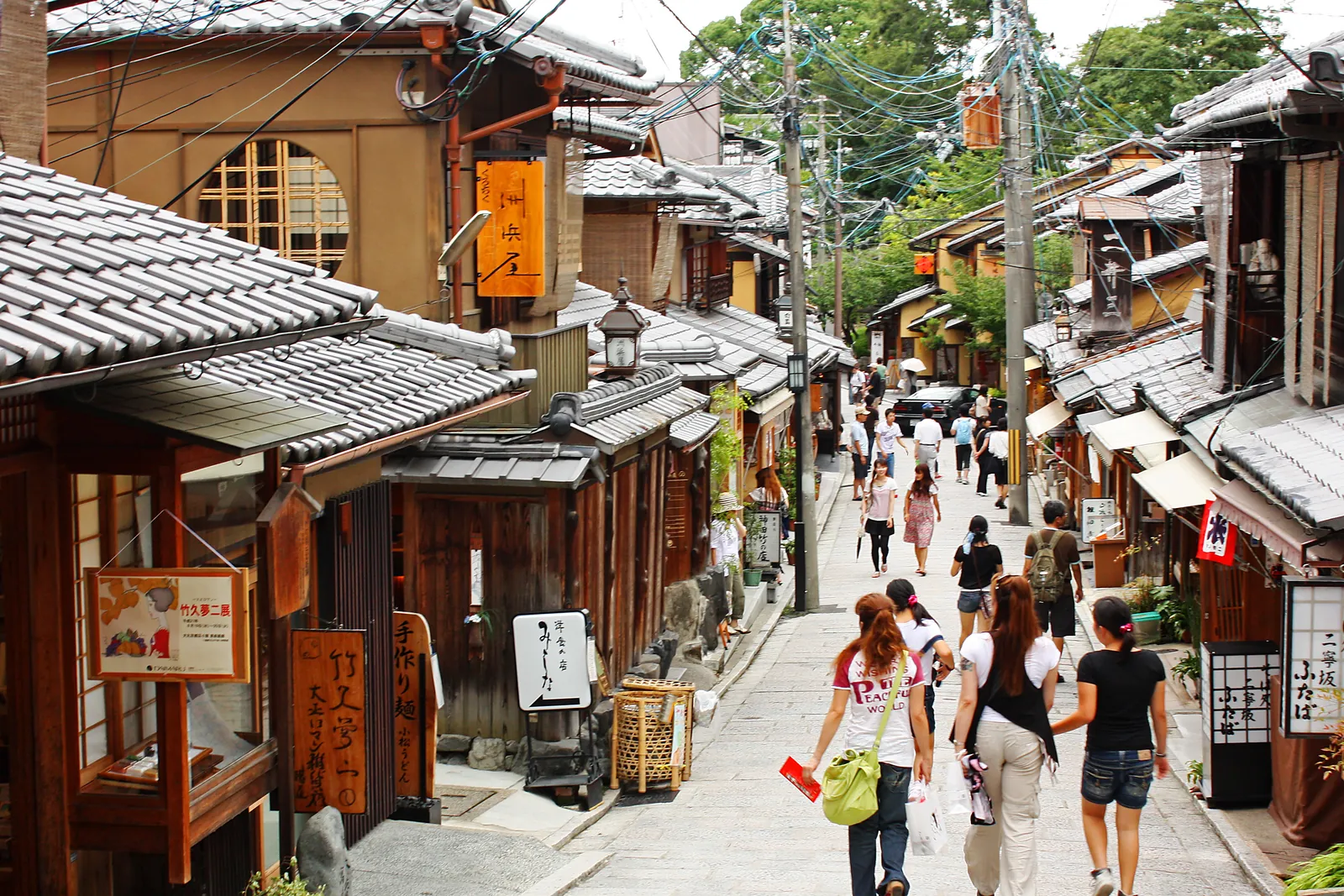 A stone-paved lane in the Sannenzaka area of Kyoto, lined with wooden shopfronts with tiled roofs and signs; a general photograph of the district, not of the tea house